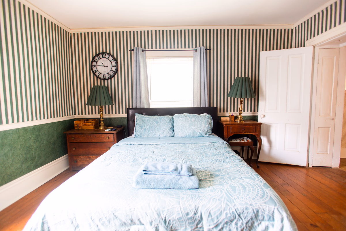 Sunlit furnished bedroom with green striped walls in a real SILK Homes property